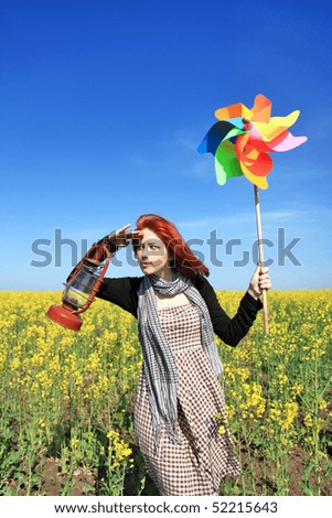 Young girl with wind turbine at rapeseed field.