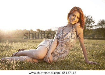 Girl at green grass field at sunset.