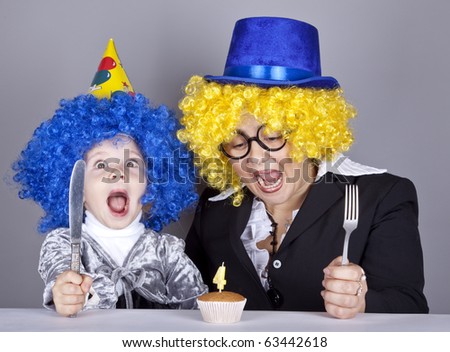 Mother and child in funny wigs and cake at birthday. Studio shot.