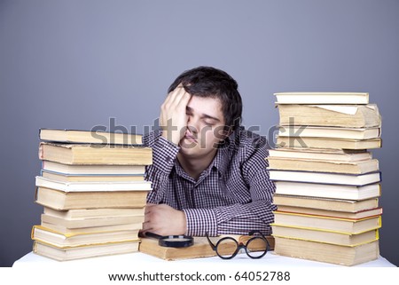 The young tired student with the books isolated. Studio shot.