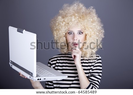 Portrait of funny girl in blonde wig with laptop. Studio shot.