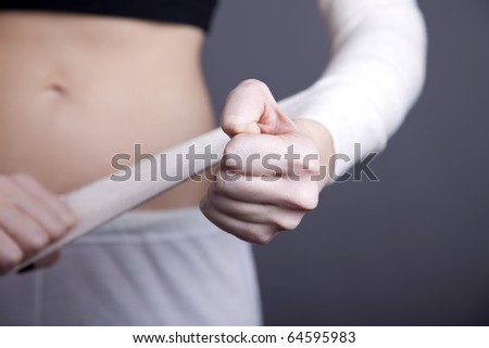 Strong girl\'s body with with elastic bandage on hand. Studio shot.