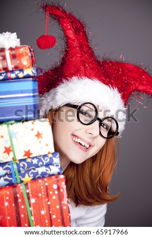 Funny red-haired girl in christmas cap with gift boxes.