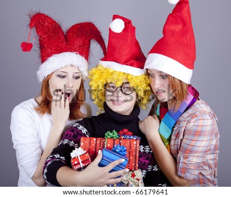 Three girlfriends in funny hats with christmas gifts. Studio shot.