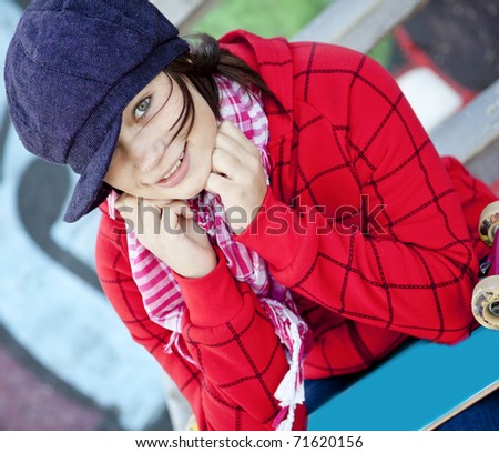 Closeup portrait of a happy young girl with skateboard and graffiti on background