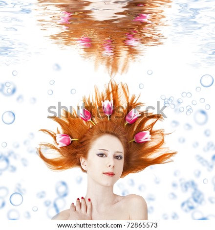 Beautiful red-haired girl with tulips in hair underwater. Art photo.