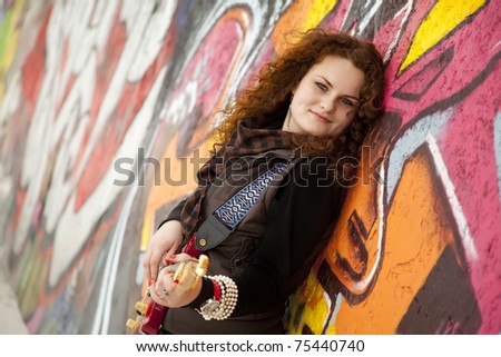 Fashion teen girl with guitar at graffiti background.