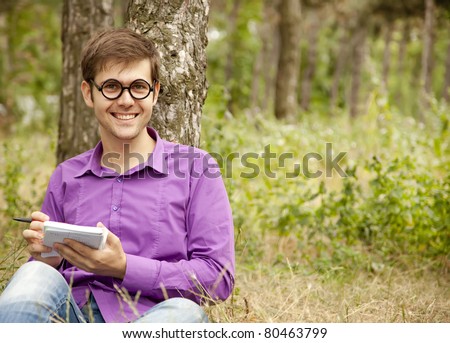 Funny men with glasses doing homework at the park.