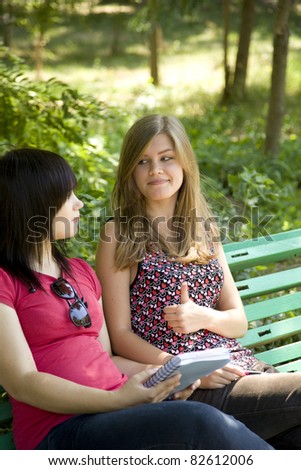 Two girlfriends doing homework at the park.