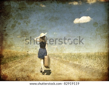 Lonely girl with suitcase at country road. Photo in old color image style.