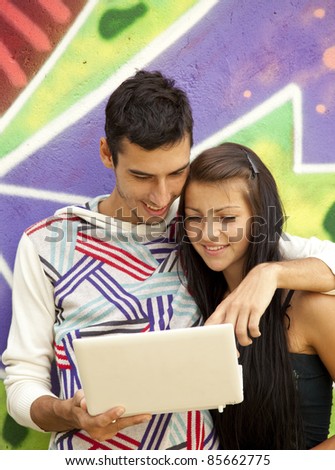 Couple with notebook near graffiti wall. Urban photo.