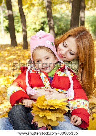 Mother and daughter in autumn yellow park.