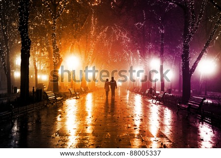 Couple walking at alley in night lights. Photo in vintage multicolor style.