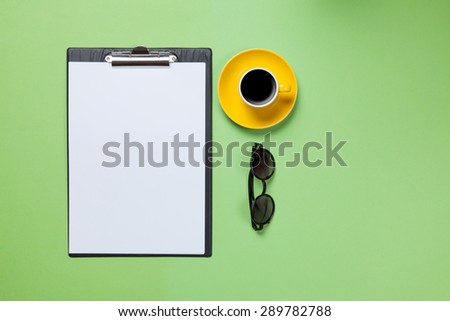 Cup of coffee and business board with glasses on green blackboard