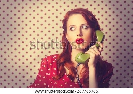 Portrait of a redhead girl with green dial phone on Polka dot background.