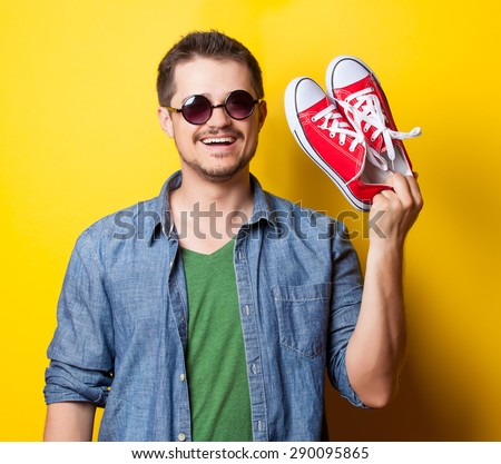 young smiling guy in shirt with mobile phone on yellow background.