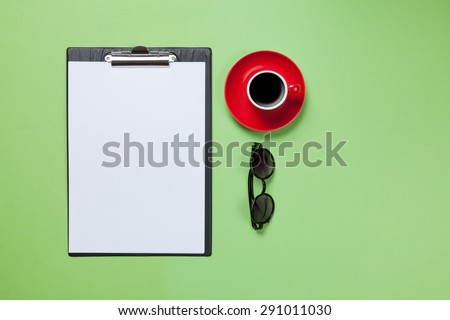 Cup of coffee and business board with glasses on green blackboard