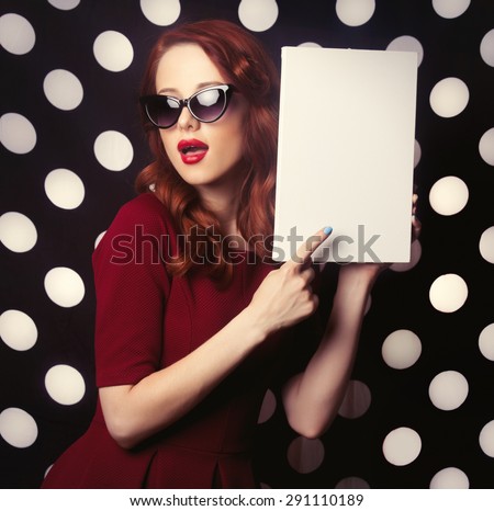 Portrait of a redhead girl with white board on black Polka dot background.