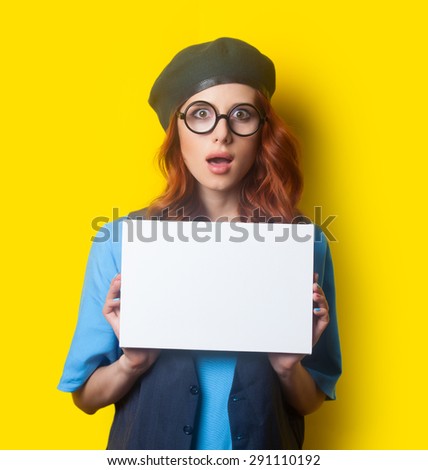 Surprised redhead girl with white board on yellow background