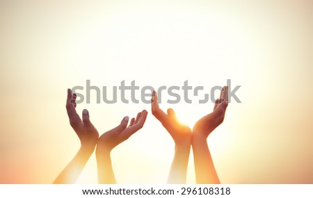 four hands on sunset background.