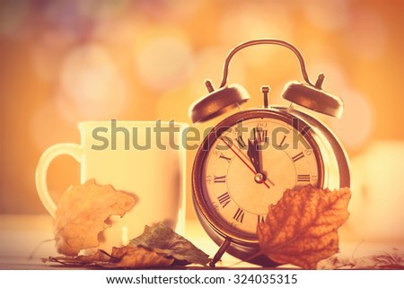 Vintage alarm clock and cup on yellow background with bokeh