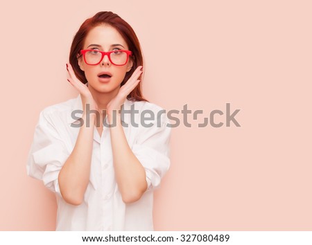 Portrait of surprised redhead woman on pink background