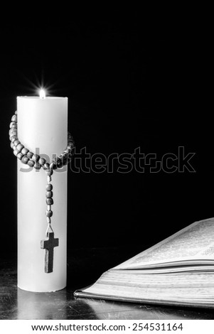 Candle with wood cross and bible on table