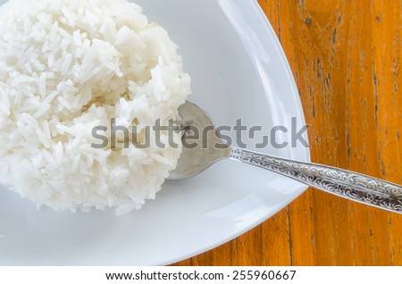 Cooked rice with a spoon on white dish.