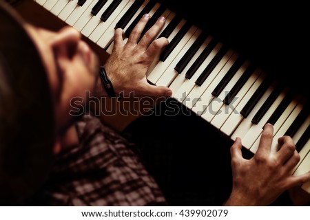Man playing piano on dramatic dark stage