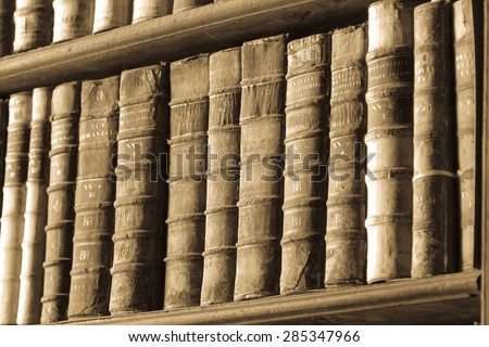 Trinity College, Dublin - April 1, 2014. Thick old books standing in a row on a shelf in the library.