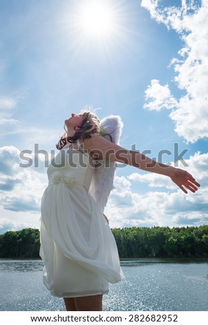 An angel woman in nature with sky and sun
