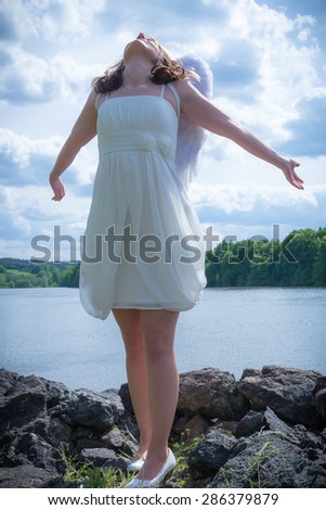 An angel woman in nature with sky and water