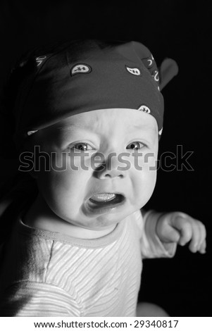 Black and white photo of crying 6 month old boy. He is wearing a striped shirt and a bandana on his head.