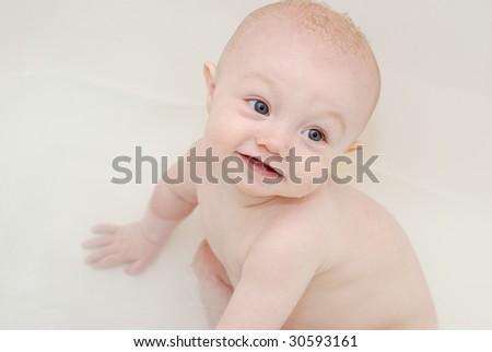 9 month old boy looking up while sitting in the bath tub