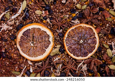 Texture of rooibos tea with dry anise, raisins, cardamom and ginger with two dry orange slices in center