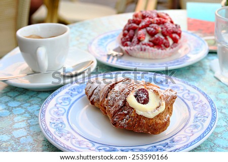 Tradition cake of region Campania Code di Aragosta on white blue plate with cup of coffee and strawbarry cake background in Sant Angelo, Ischia