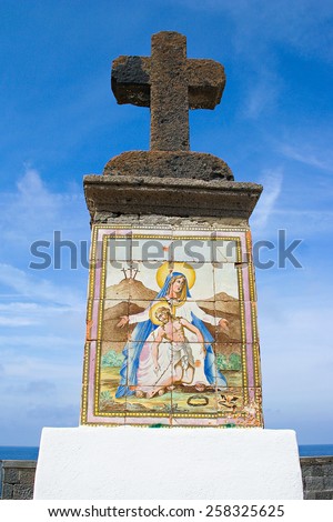 Details of religion architecture with big stone cross and picture with Jesus and Madonna, Forio, Ischia island, Italy