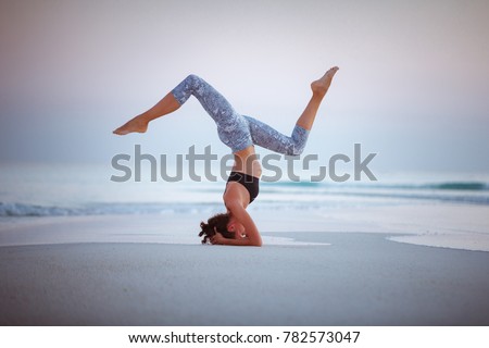 Young woman practice balance asanas on Summer yoga session on a beautiful golden beach of Maldives on a yoga tour, Fulhadhoo, Salamba Sirsasana - supported headstand