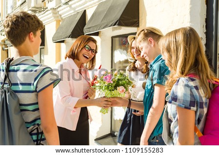 Group teenagers of high school students congratulate their teacher with bouquet of flowers. Teacher\'s Day.