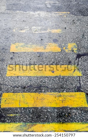 Shabby yellow stripes crosswalk on the old concrete surface