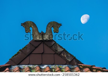 Roof top of the village house with the moon & blue sky on background in early morning. Fretted apex on the roof