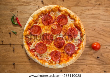 Delicious hot pizza pepperoni with different spices on wooden table ready to eat