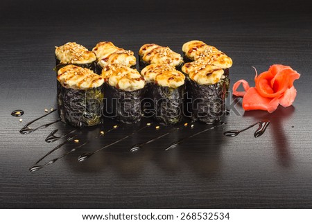 Japanese baked sushi and roll set on a wooden black table with ginger and sauce