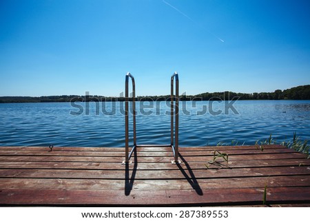 View on a trees and wooden pier by the lake with yellow water bikes