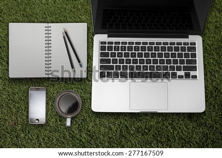 Laptop tablet computer with    and cup of coffee on grass Simple workspace or coffee break with web surfing.