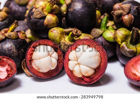 Mangosteen and cross section showing the thick purple skin and white flesh of the queen of friuts.