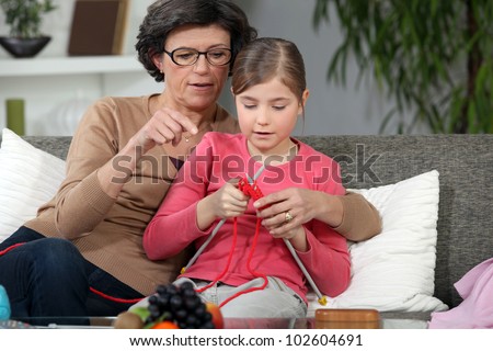 Woman teaching how to knit to little girl