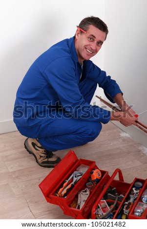 Plumber kneeling by tool box