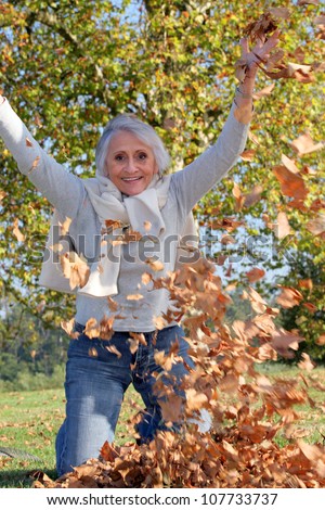 grandmother playing with a heap of dead leaves