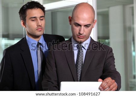 Two young businessmen stood with portable computer